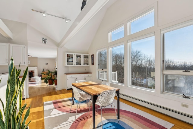 sunroom with a baseboard radiator, lofted ceiling, track lighting, and a brick fireplace