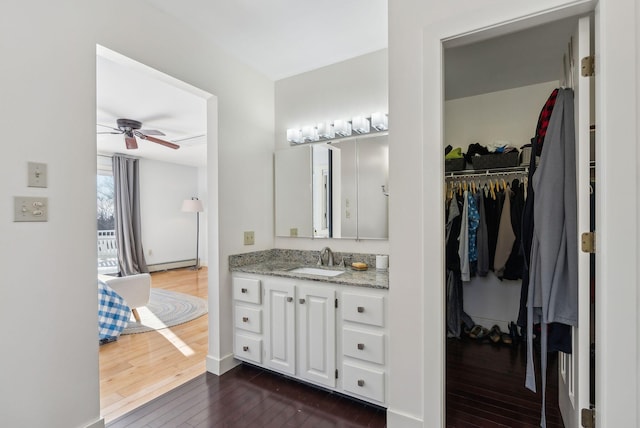 bathroom with hardwood / wood-style flooring, a baseboard radiator, vanity, and ceiling fan