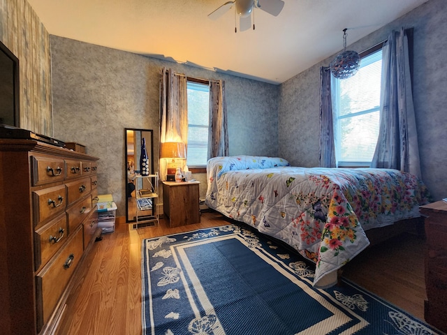 bedroom featuring multiple windows, light hardwood / wood-style floors, and ceiling fan