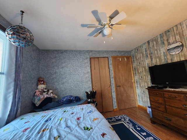 bedroom with multiple closets, wood-type flooring, and ceiling fan