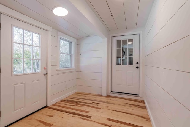 doorway to outside featuring light hardwood / wood-style floors and wooden walls