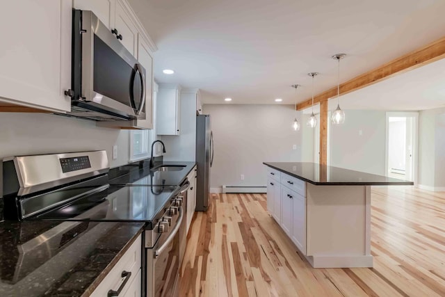 kitchen with light hardwood / wood-style floors, white cabinetry, hanging light fixtures, and appliances with stainless steel finishes