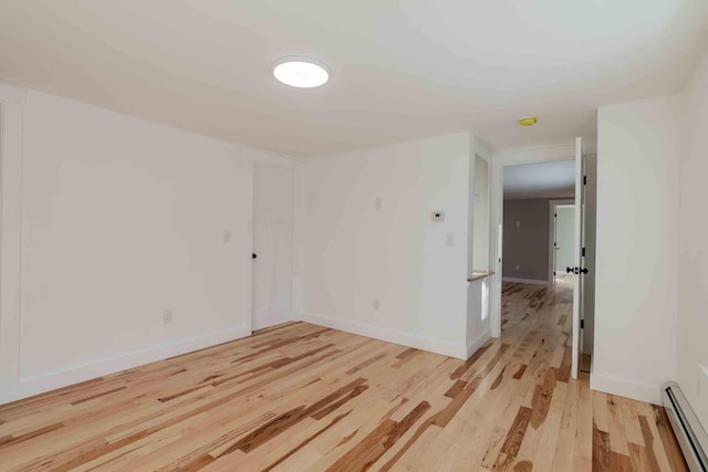 spare room with light wood-type flooring and a baseboard heating unit