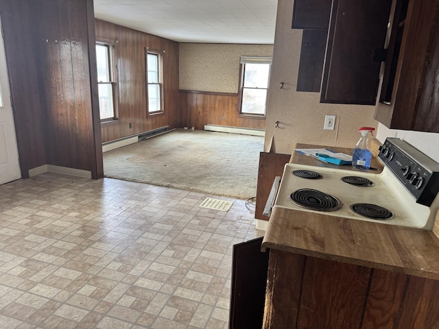 kitchen featuring baseboard heating, white range with electric cooktop, wood walls, and light colored carpet