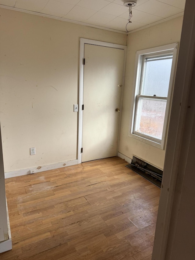 empty room with light hardwood / wood-style floors and crown molding