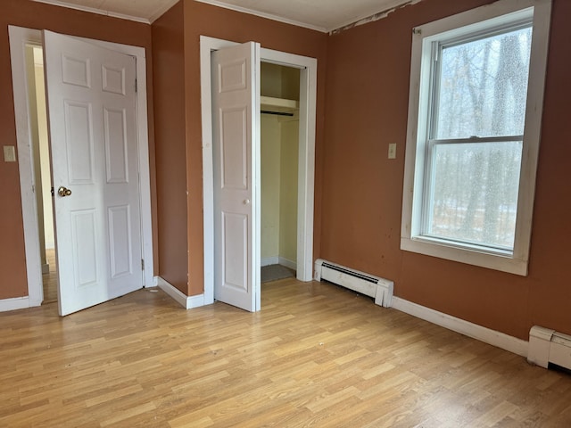 unfurnished bedroom with light hardwood / wood-style flooring, a closet, a baseboard heating unit, and crown molding