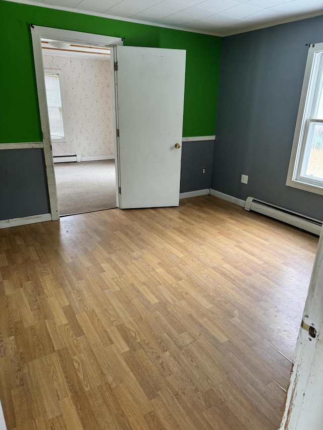 unfurnished room featuring light wood-type flooring and a baseboard heating unit