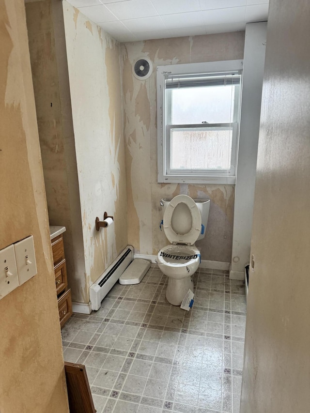 bathroom featuring vanity, a drop ceiling, toilet, and baseboard heating