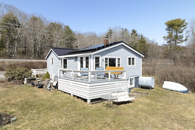 283 Mills Rd, Newcastle, ME 04553 - rear view of house with a chimney, metal roof, roof mounted solar panels, and a lawn