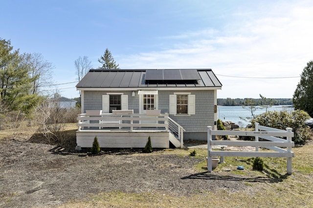 283 Mills Rd, Newcastle, ME 04553 - view of front of property with roof mounted solar panels, metal roof, fence, a deck with water view, and a standing seam roof