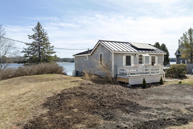 283 Mills Rd, Newcastle, ME 04553 - view of front of house with a deck with water view, a standing seam roof, solar panels, and metal roof