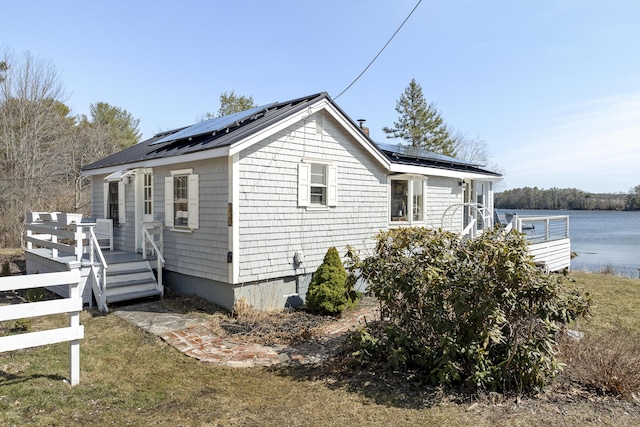 283 Mills Rd, Newcastle, ME 04553 - view of home's exterior with fence, a wooden deck, metal roof, and roof mounted solar panels