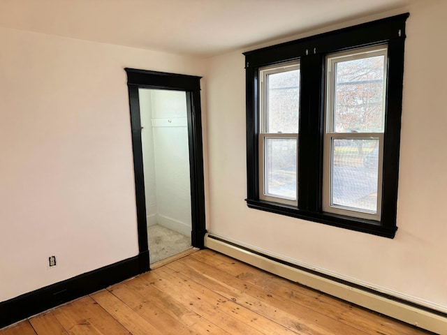 unfurnished room featuring light wood-type flooring and a baseboard radiator