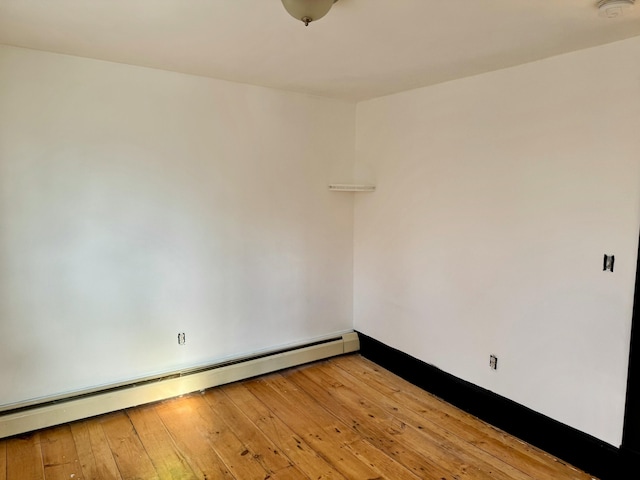 empty room with hardwood / wood-style floors and a baseboard radiator