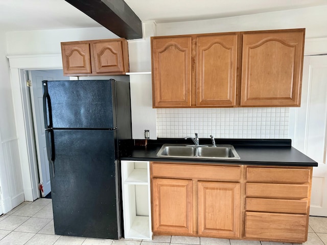 kitchen with tasteful backsplash, black refrigerator, sink, and light tile patterned flooring