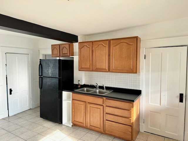 kitchen featuring backsplash, black refrigerator, light tile patterned floors, and sink