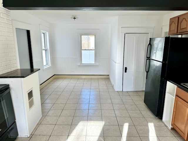 kitchen featuring light tile patterned floors, black fridge, and range