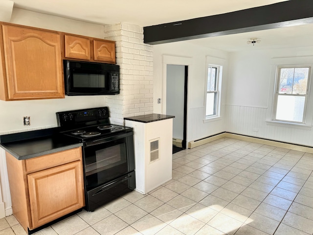 kitchen featuring black appliances, light tile patterned flooring, baseboard heating, and beam ceiling