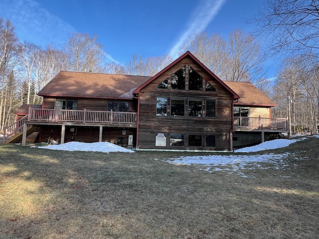 snow covered house with a wooden deck and a lawn