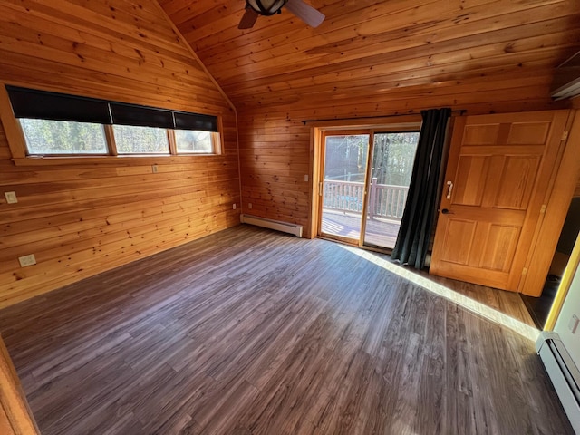 empty room featuring wood walls, vaulted ceiling, dark wood-type flooring, and a baseboard heating unit