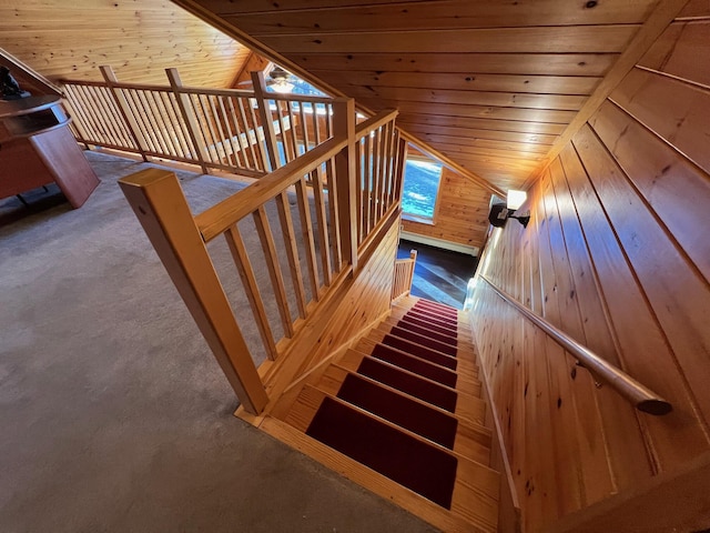 stairway with a healthy amount of sunlight, vaulted ceiling, wooden walls, and wood ceiling