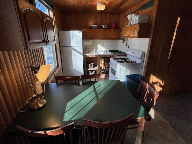 kitchen with wooden walls, plenty of natural light, wooden ceiling, and white appliances