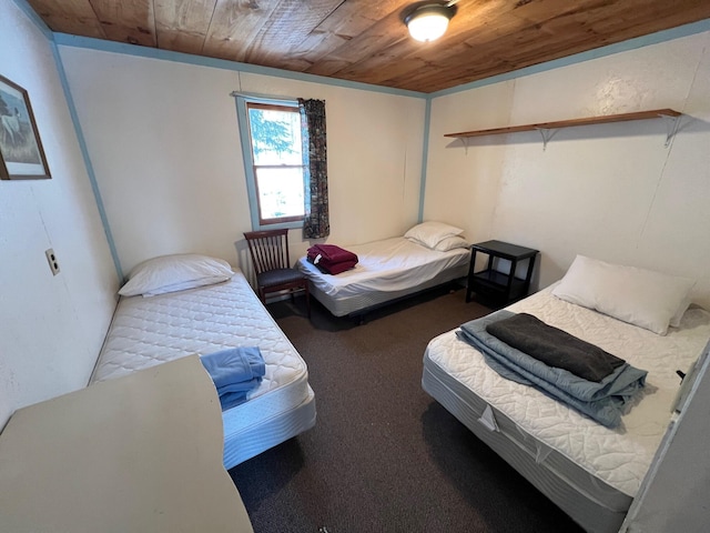 bedroom featuring dark colored carpet and wooden ceiling