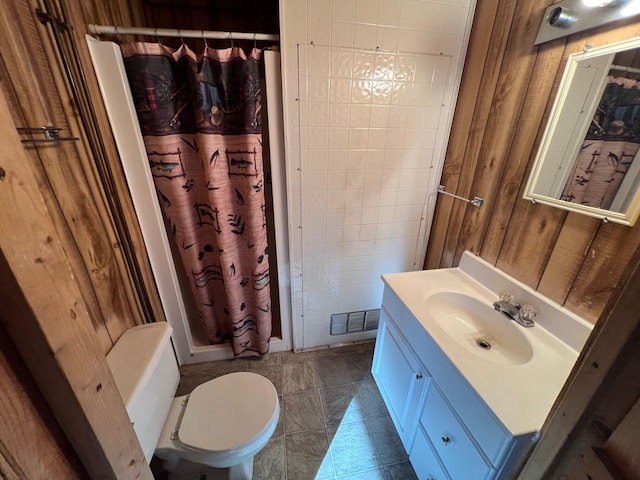 bathroom with tile patterned floors, vanity, toilet, and wooden walls