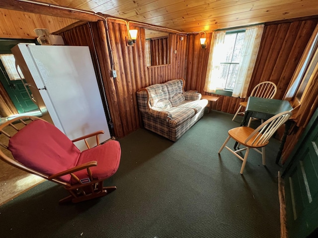 sitting room with carpet flooring, wooden walls, and wood ceiling