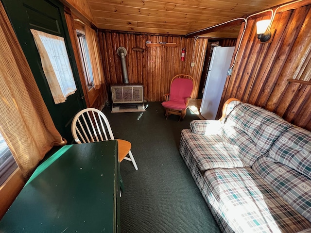 sitting room with wood ceiling, carpet floors, wooden walls, and a wood stove