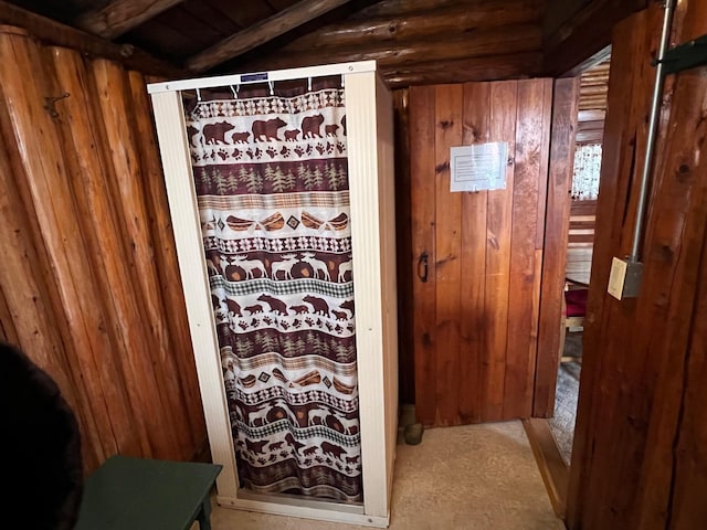 bathroom featuring beamed ceiling and wood walls