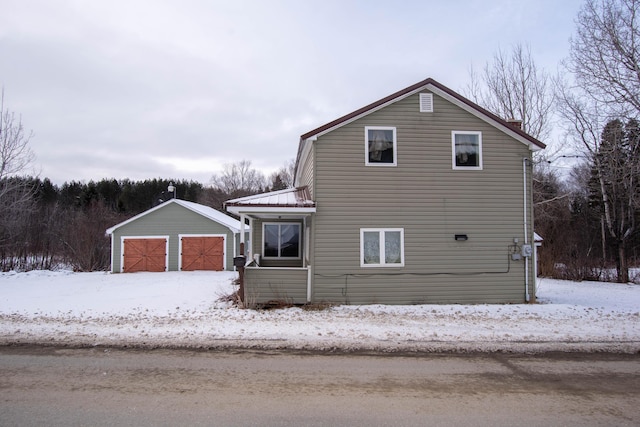 view of snowy exterior featuring an outbuilding and a garage