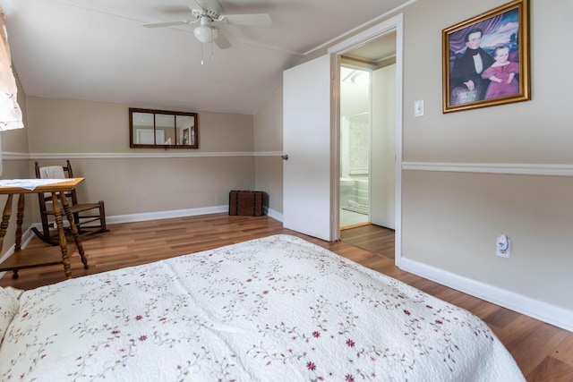 bedroom with hardwood / wood-style floors, vaulted ceiling, ensuite bath, and ceiling fan