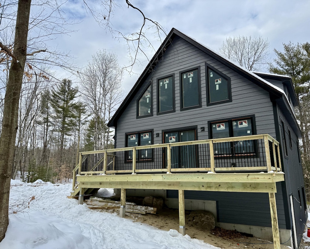 snow covered back of property featuring a wooden deck