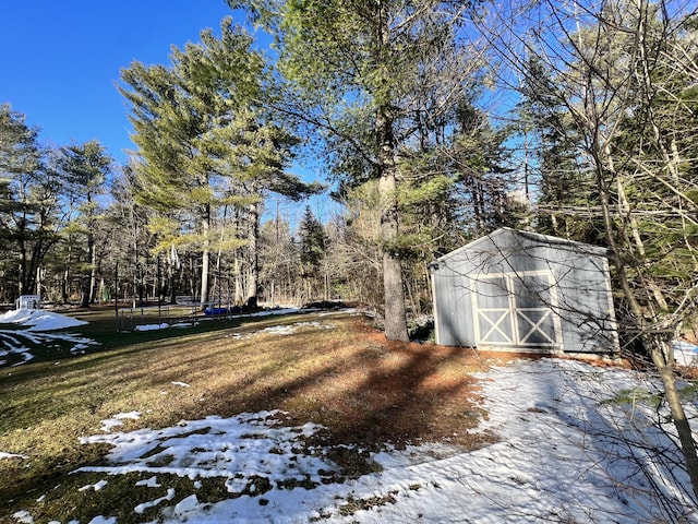 snowy yard featuring a shed