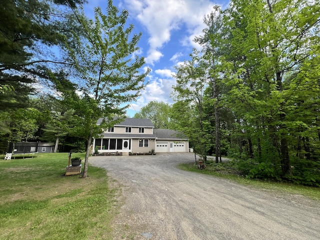 701 Stetson Rd, Exeter, ME 04435 - view of front of home featuring a trampoline, driveway, a garage, a front lawn, and a sunroom