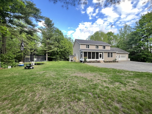 701 Stetson Rd, Exeter, ME 04435 - view of green lawn featuring a trampoline, a sunroom, an attached garage, driveway, and view of scattered trees