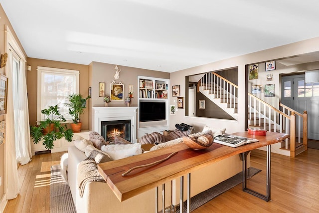 living room with built in shelves and light wood-type flooring