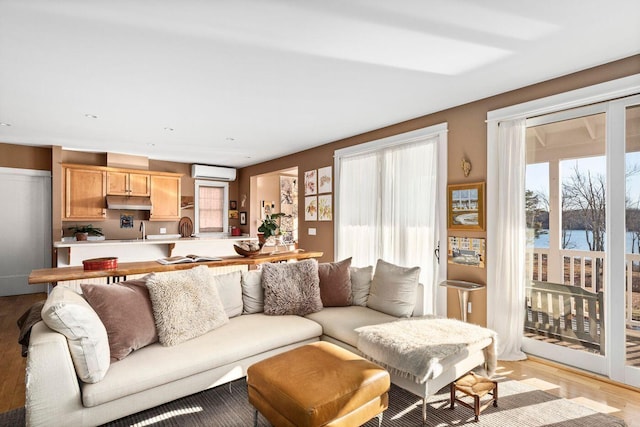 living room with a water view, sink, a wall mounted AC, and light hardwood / wood-style flooring