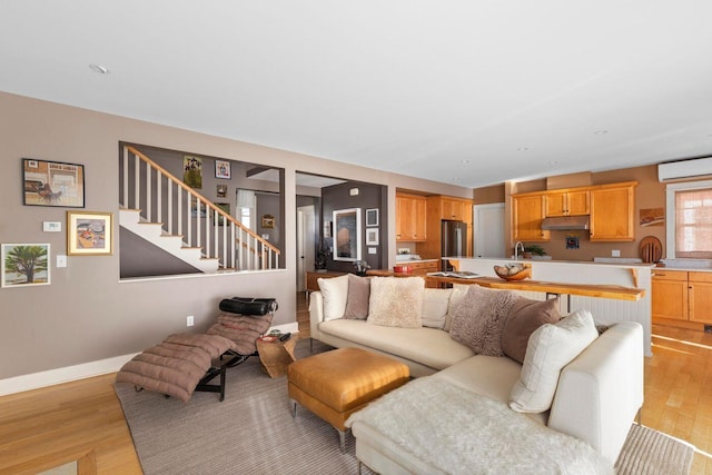 living room with a wall mounted AC and light wood-type flooring