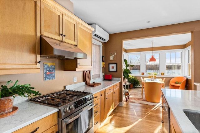 kitchen with an AC wall unit, decorative light fixtures, stainless steel appliances, light stone countertops, and light wood-type flooring