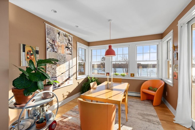 sunroom featuring a baseboard heating unit, a wealth of natural light, and a water view