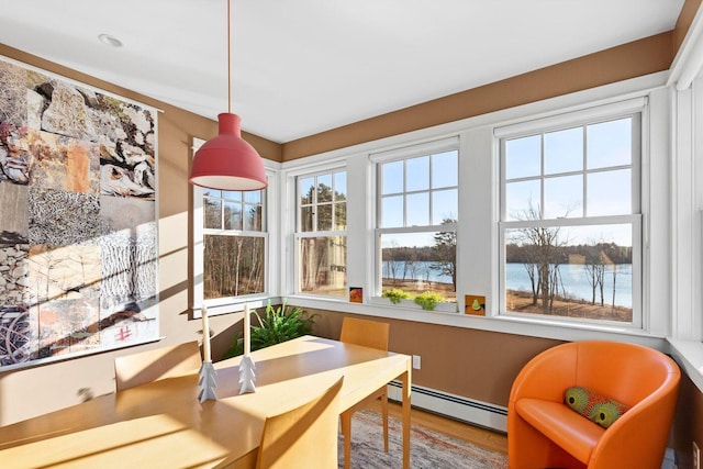 sunroom with a baseboard heating unit and a water view