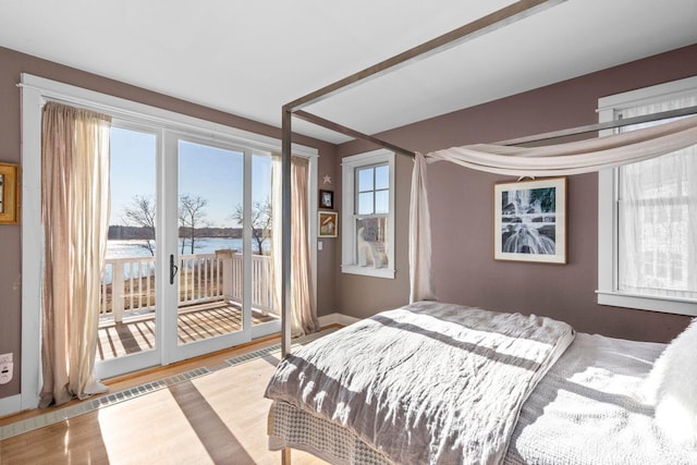 bedroom featuring wood-type flooring, a water view, and access to outside