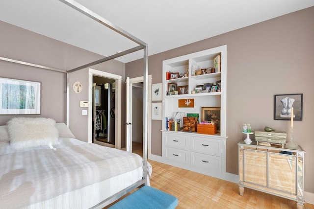 bedroom with a walk in closet and light hardwood / wood-style floors