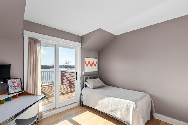 bedroom with a water view, lofted ceiling, access to exterior, and light hardwood / wood-style floors