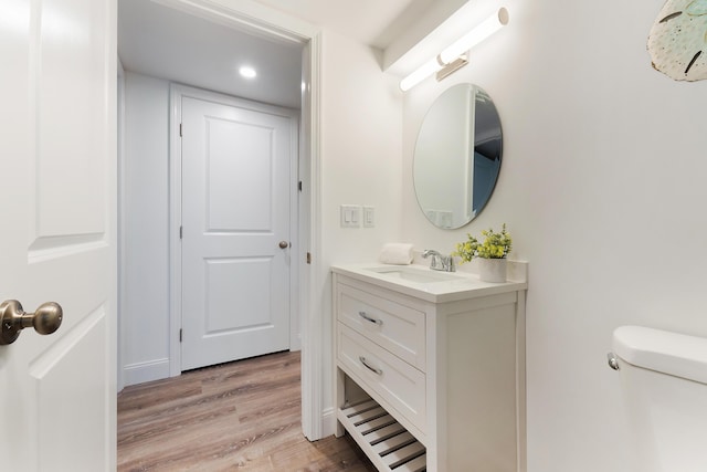 bathroom featuring toilet, vanity, and hardwood / wood-style floors