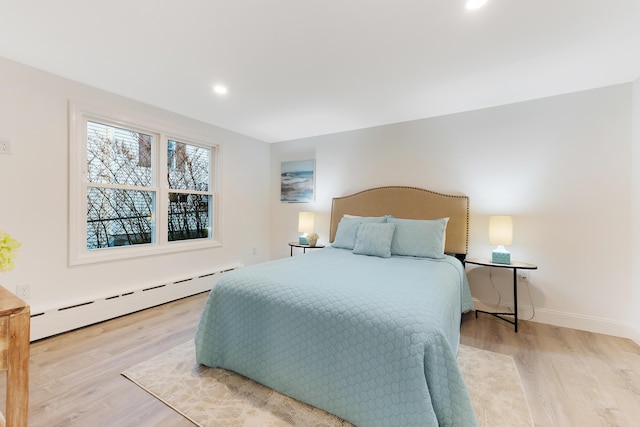 bedroom featuring a baseboard heating unit and light wood-type flooring