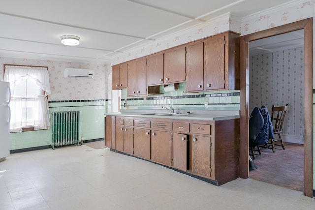 kitchen featuring radiator, sink, white refrigerator, a wall unit AC, and crown molding