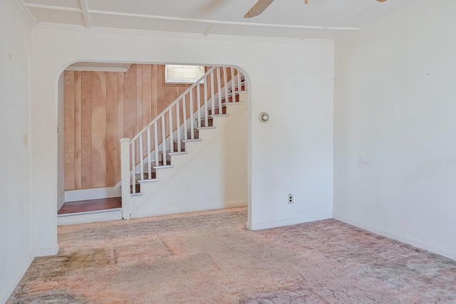 stairs with ceiling fan, wooden walls, and carpet floors